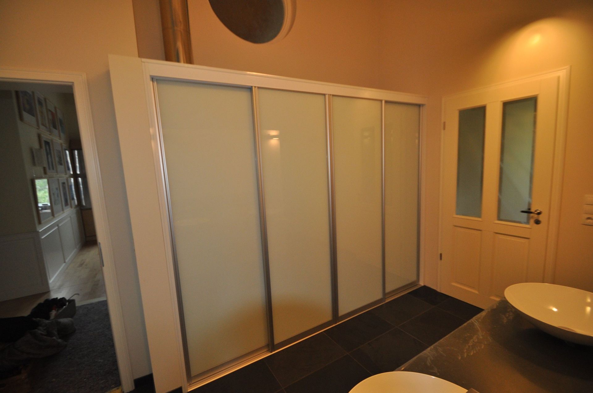 Weißer Schiebetürenschrank mit Milchglas in einem Badezimmer.