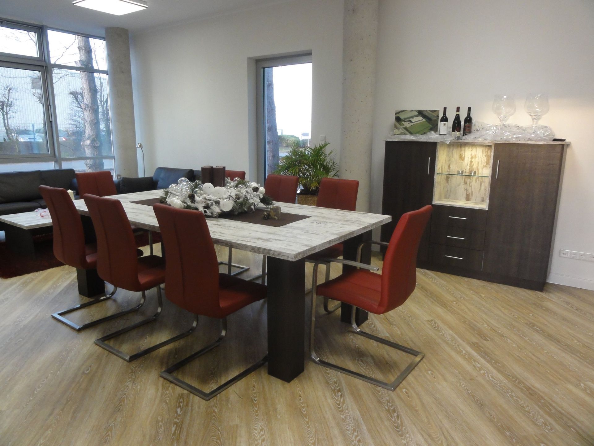 Esszimmer mit großem Tisch, roten Stühlen und einem Schrank.