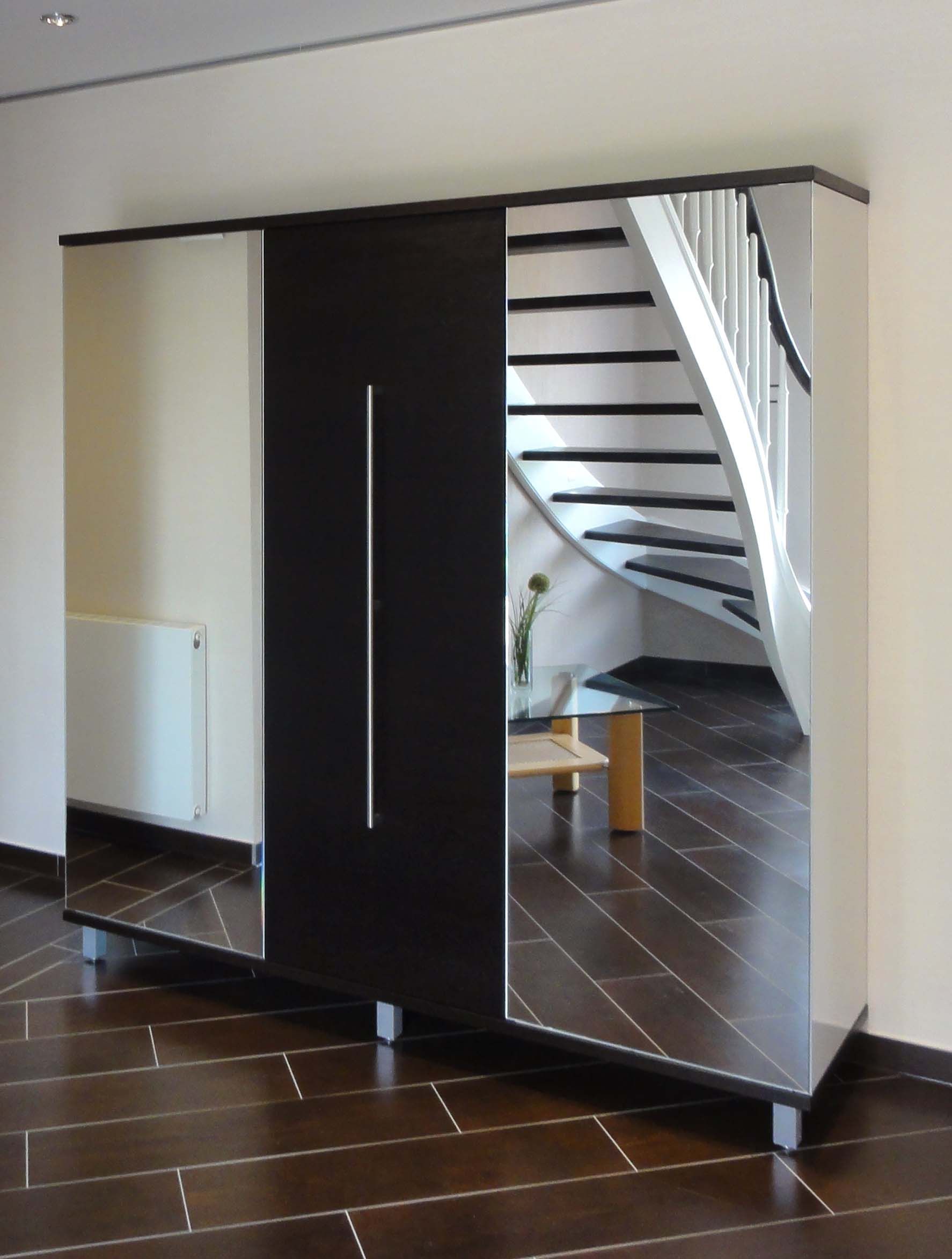 Moderner Kleiderschrank mit verspiegelten und schwarzen Türen in einem Raum mit einer im Spiegel reflektierten Treppe.