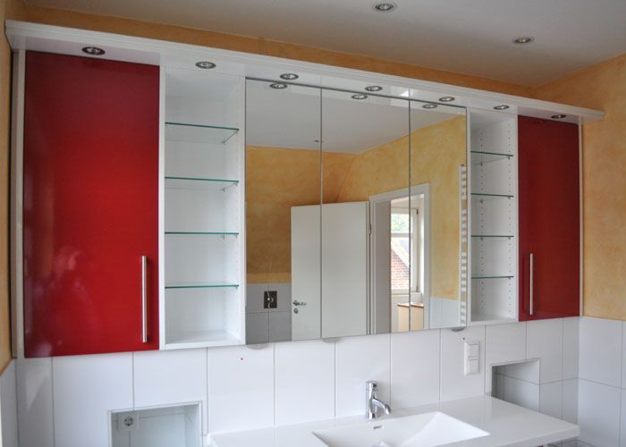 Rot-weißer Badezimmerschrank über einem Waschbecken, mit einem verspiegelten Medizinschrank.