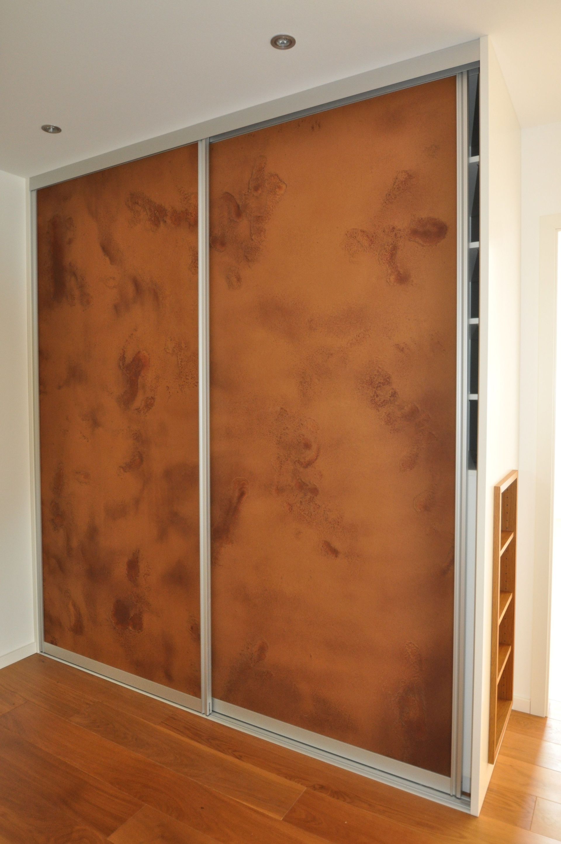 Schiebetüren für Schränke mit braun gesprenkeltem Muster und silberner Verzierung in einem weißen Raum.