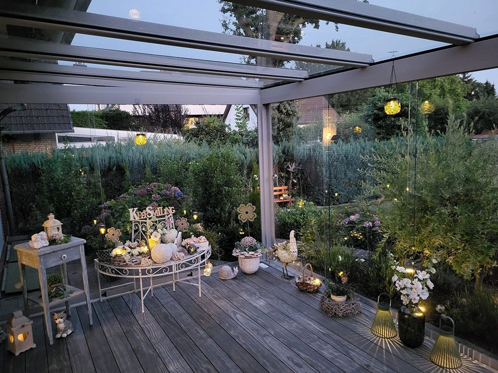 In der Abenddämmerung mit Lichterketten und Blumen dekorierte Terrasse.