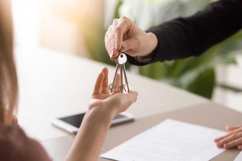 Una mujer recibe un juego de llaves de un agente inmobiliario.