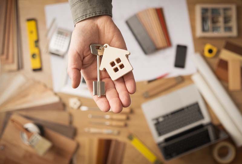 Una persona sostiene una llave con un llavero de casa en su mano.
