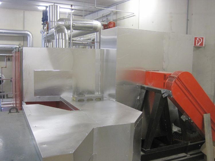 Industriemaschinen mit Metallrohren und orangefarbenen Anlagen in einem Fabrikraum