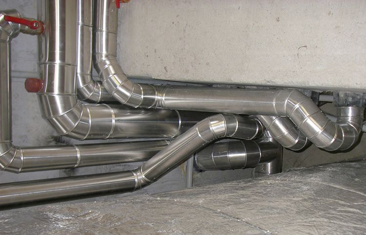 Metallene Lüftungskanäle verlaufen entlang des Kellerbodens und der Kellerwand und sind mit silberisolierten Rohren versehen.
