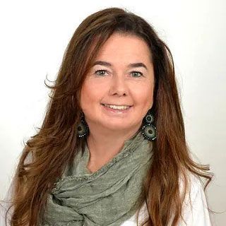 Porträt einer lächelnden Frau mit langen braunen Haaren, die einen grauen Schal und Ohrringe trägt, vor weißem Hintergrund