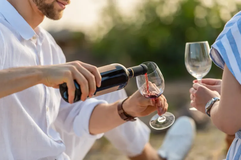 Un hombre está sirviendo vino en una copa para una mujer.