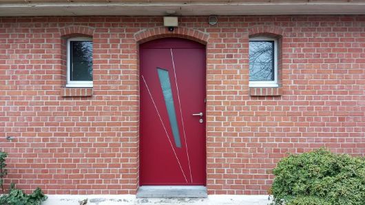 Porte d'entrée rouge de maison en brique