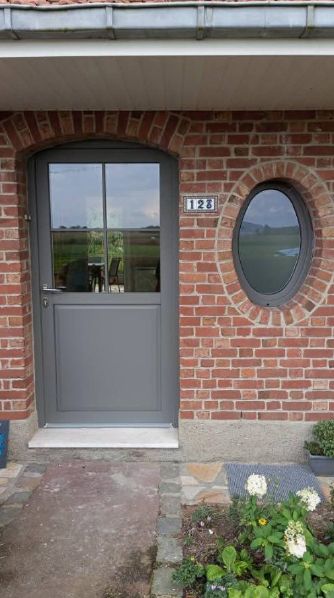 Porte d'entrée et oeil de boeuf d'une maison en brique