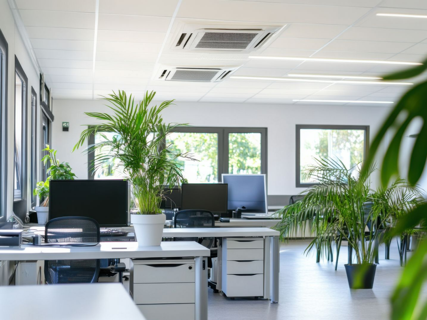 Un espace de travail avec bureaux et ordinateur, équipé de climatiseurs gainables.