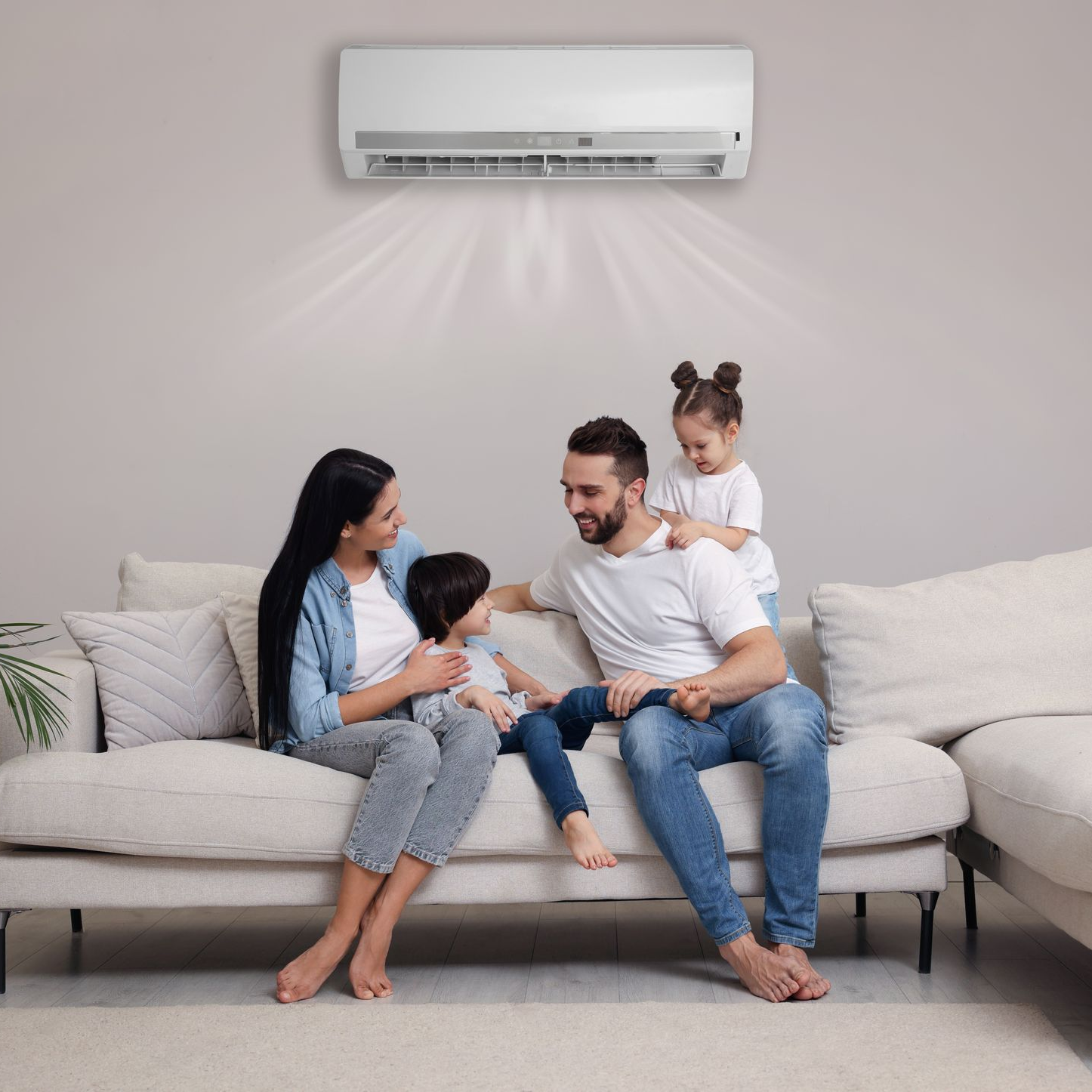 Une famille assise sur un canapé sous un climatiseur, profitant de la fraîcheur.