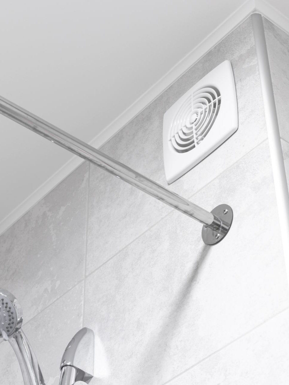 Grille d'aération blanche au dessus d'une douche.