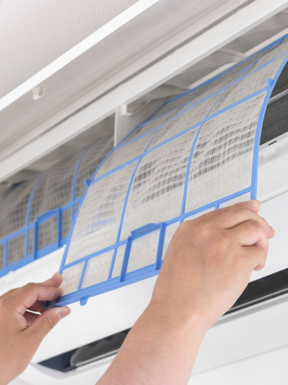 Une personne retire le filtre d'un climatiseur.