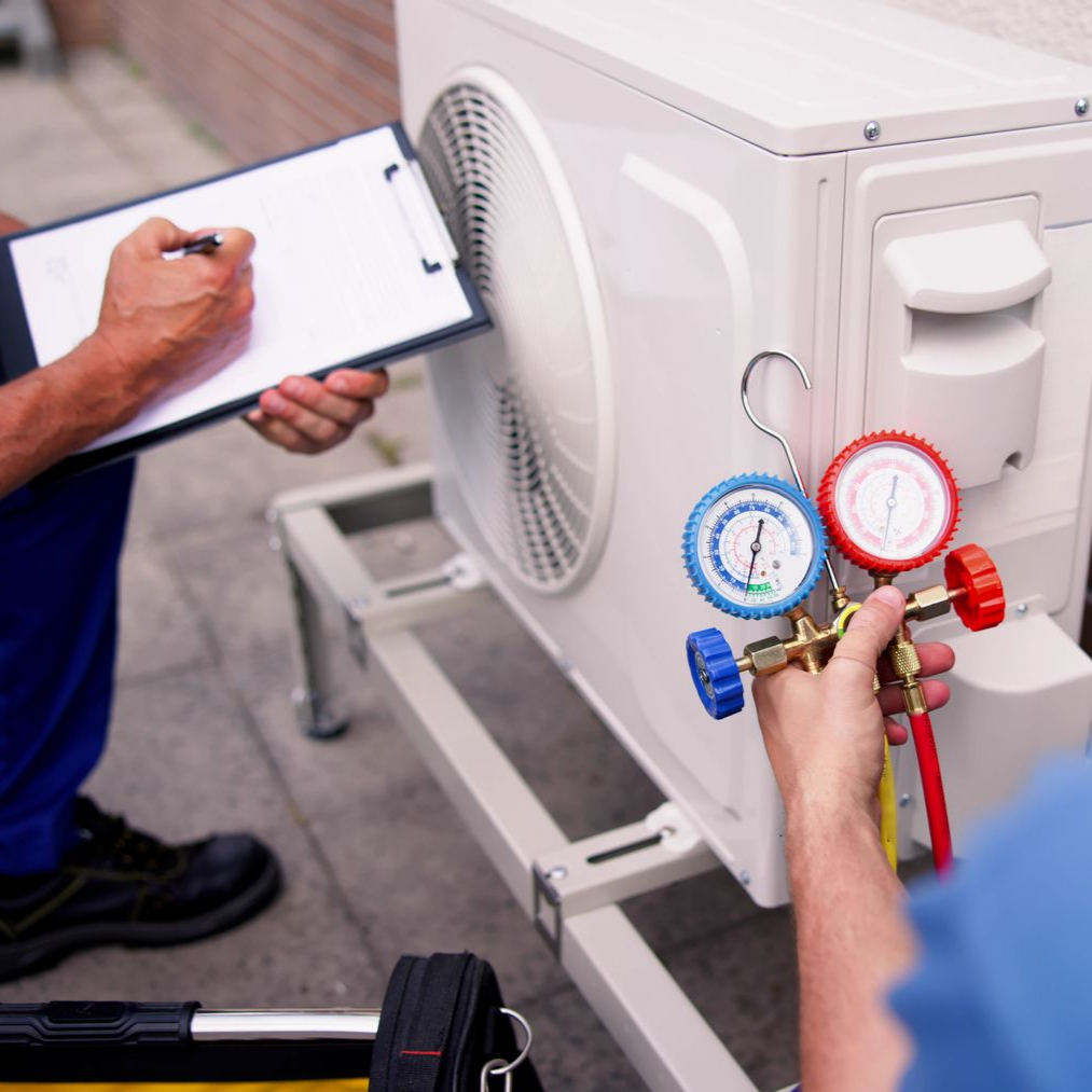 Des techniciens qui contrôlent une unité extérieure de climatisation.