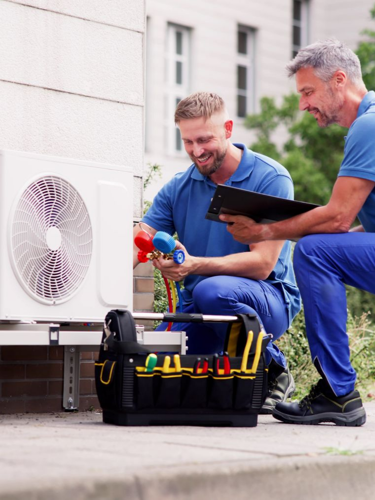 Deux techniciens travaillent sur une unité extérieure de climatisation.