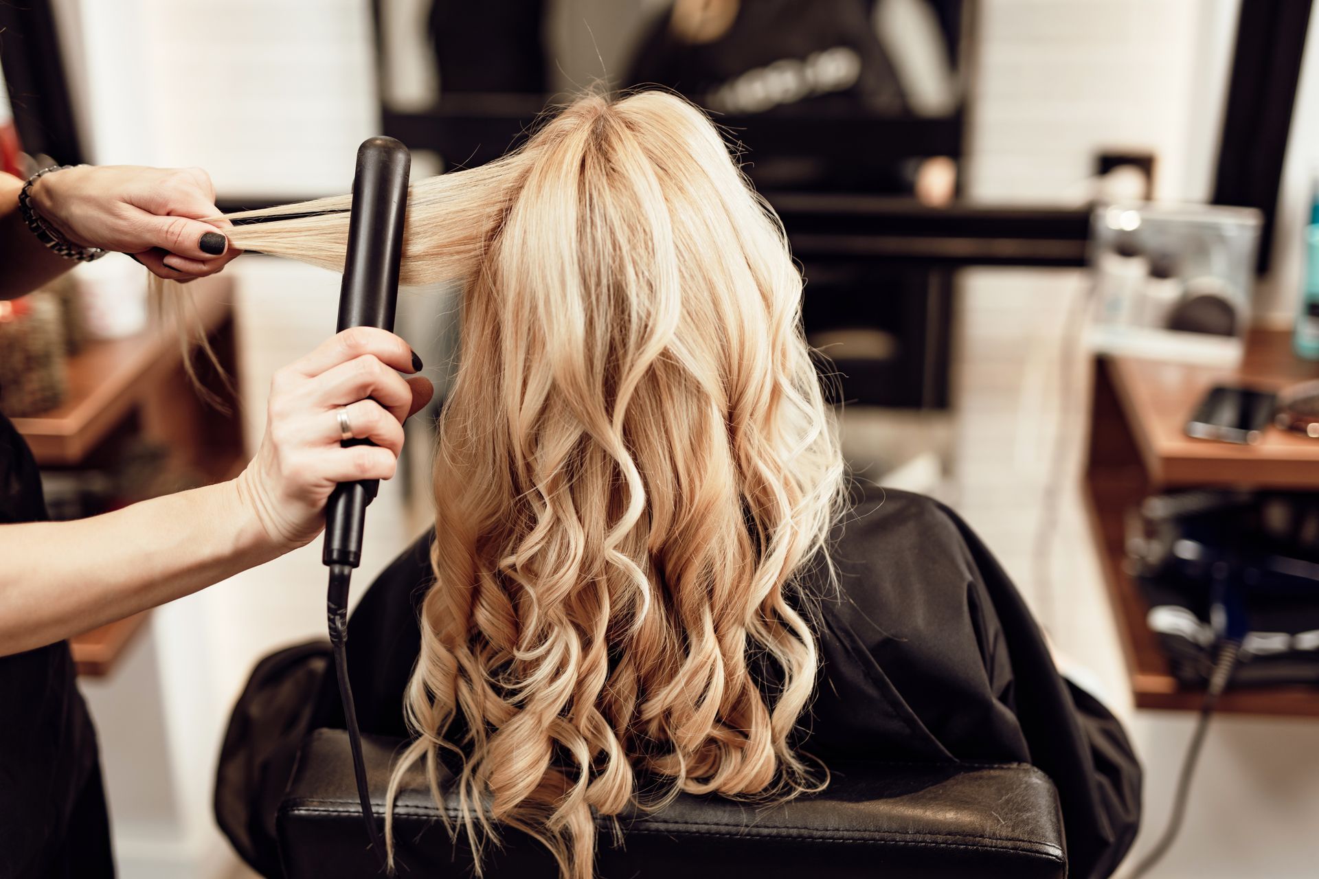 Coiffeuse bouclant de longs cheveux dans un salon