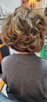 Personne aux cheveux courts et bouclés, vue de dos, portant un pull à l'intérieur.
