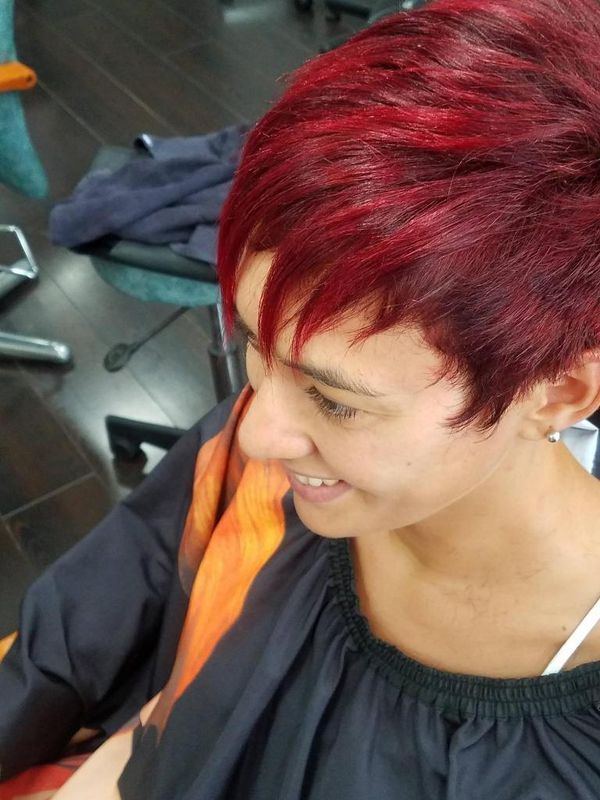 Personne aux cheveux rouges courts, souriante et regardant vers le bas, portant un haut à bordure.