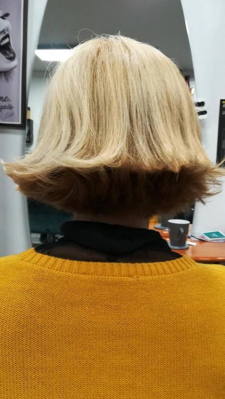 Vue de dos d'une personne aux cheveux courts, coiffée au carré, portant un pull à l'intérieur.