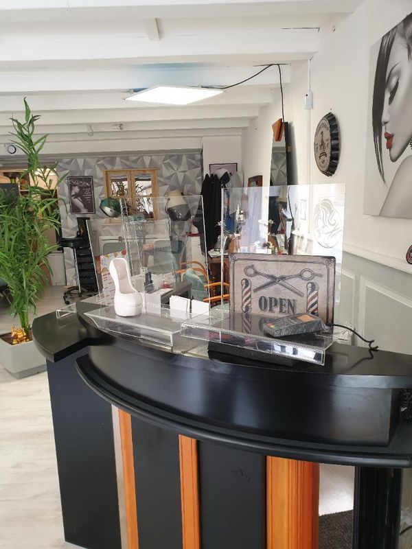 Comptoir d'accueil du salon avec écrans et panneau OUVERT dans un intérieur.