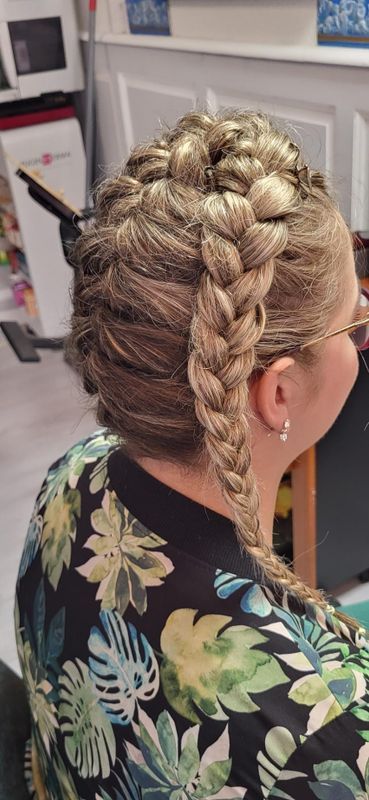 Vue de profil d'une coiffure tressée avec une tresse plus épaisse sur le dessus et une longue tresse sur le côté, réalisée en salon.