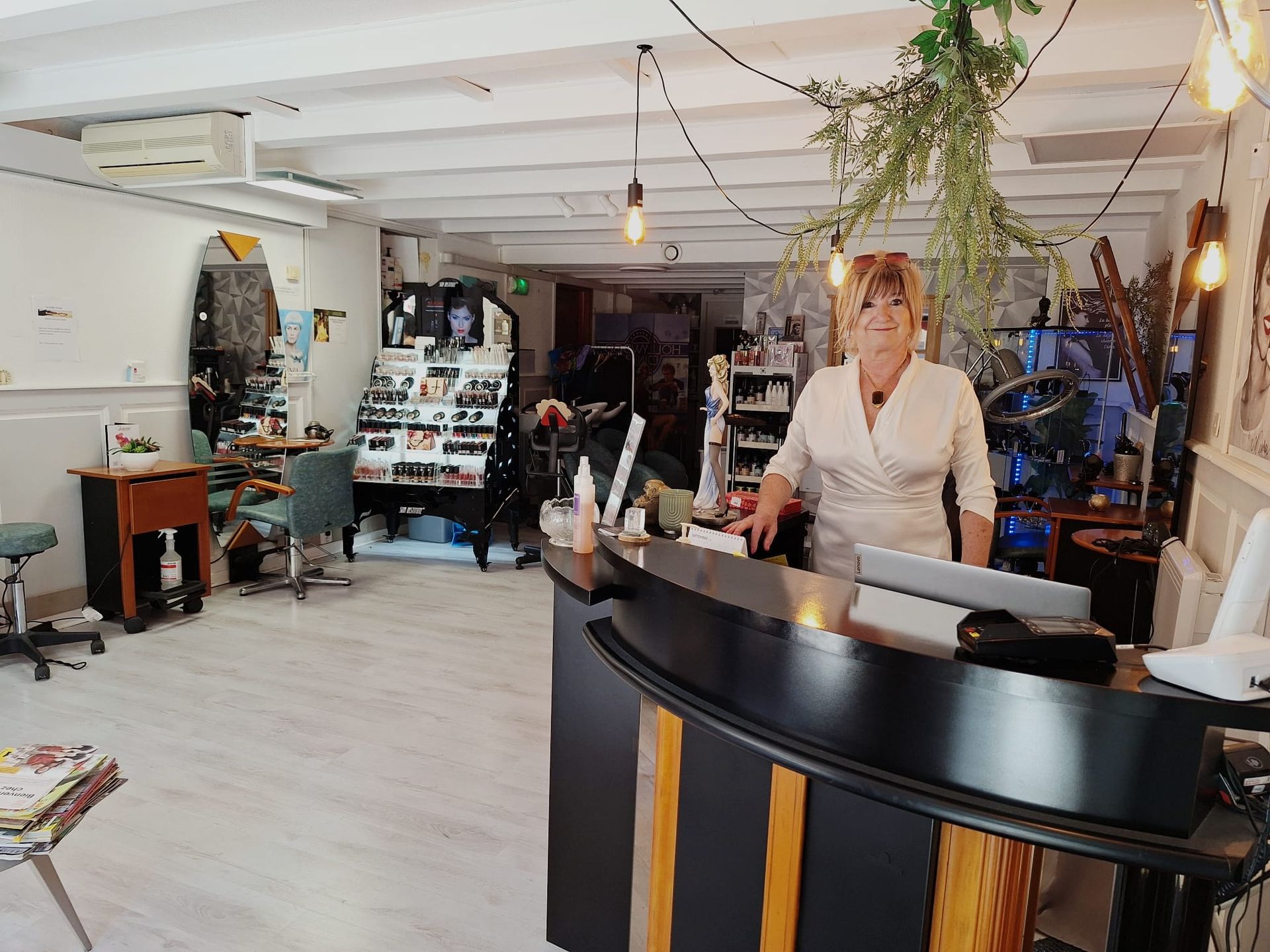 Une femme derrière un comptoir d'accueil incurvé, dans l'intérieur lumineux et rempli de plantes d'un magasin.