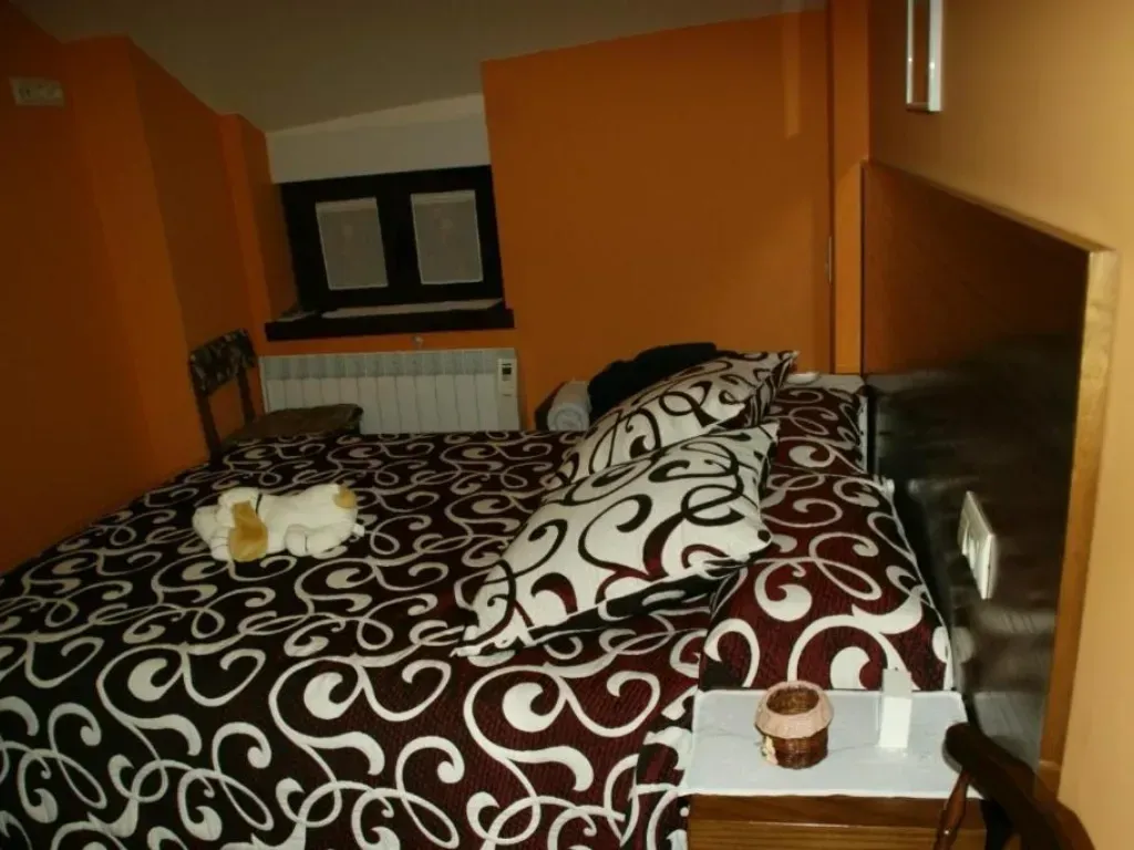 Dormitorio con paredes naranjas, una cama con ropa de cama y almohadas estampadas en tonos marrones y blancos.