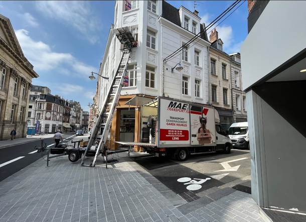 Un monte-meuble  déplace un meuble au  2e étage