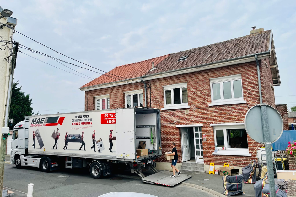 Un homme transporte un carton et s'apprête à le déposer dans un camion de déménagement