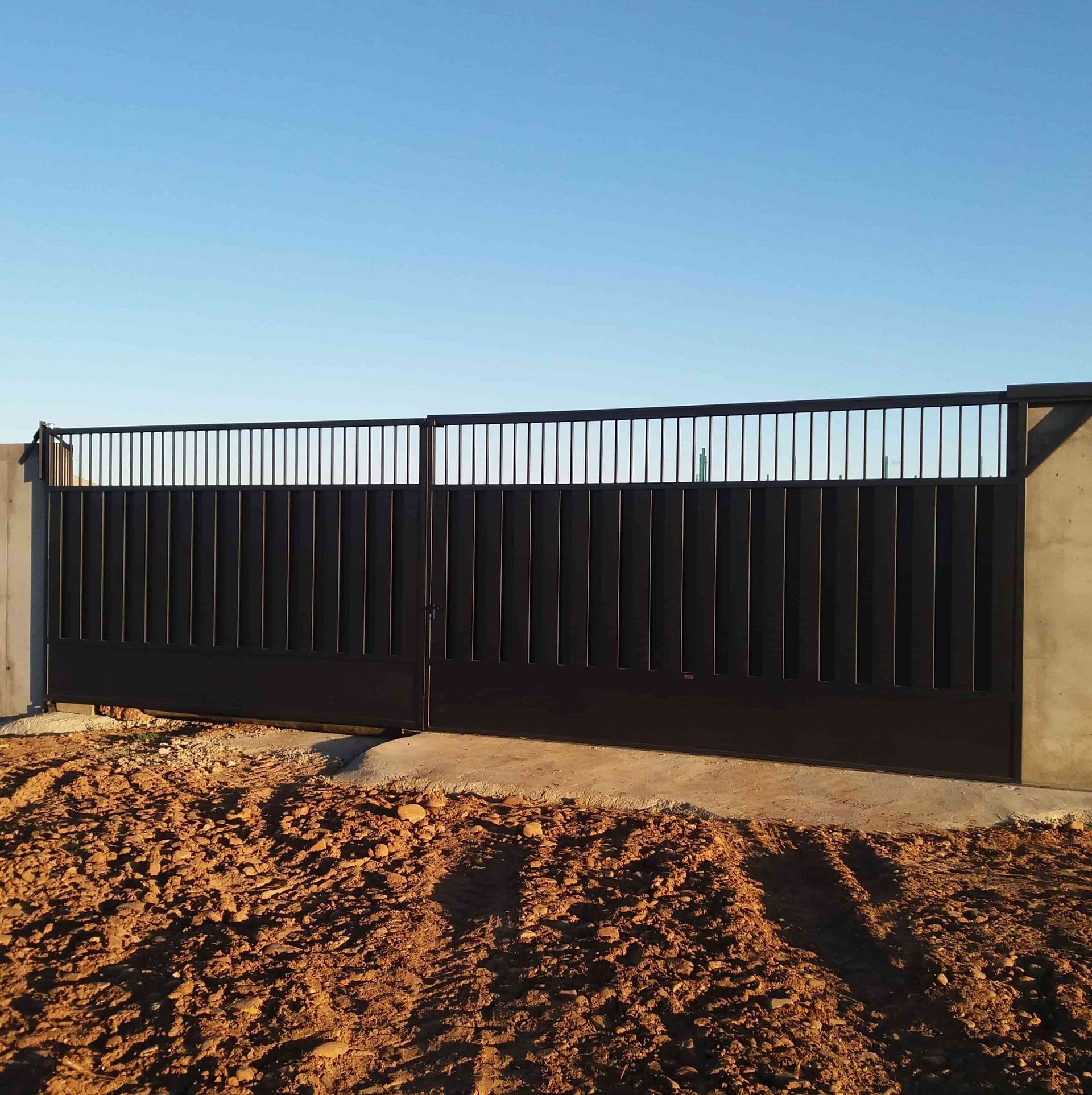 Una puerta negra está en medio de un campo de tierra.