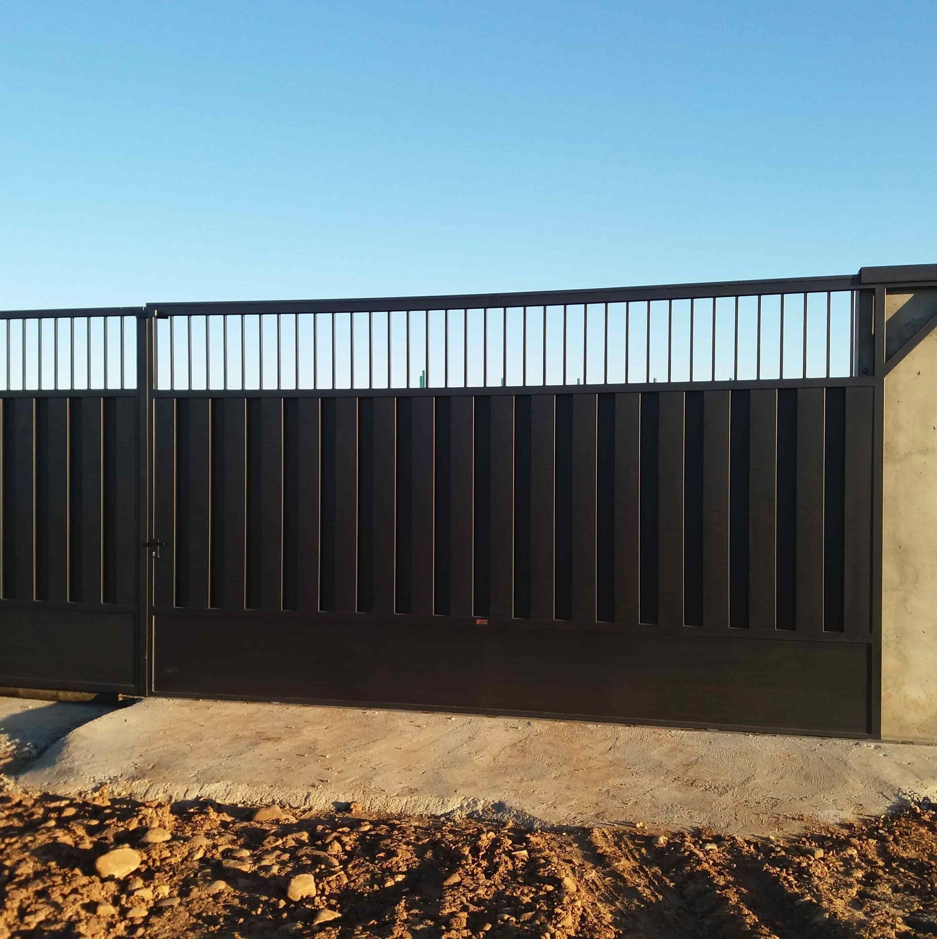 Una valla negra con un cielo azul al fondo