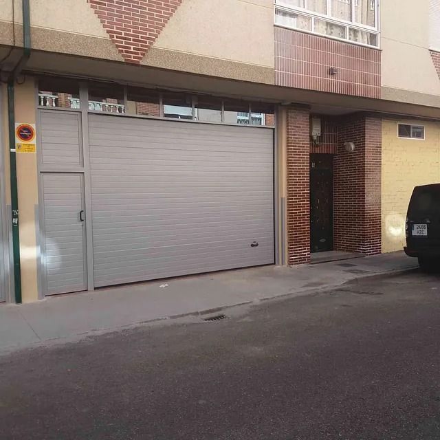 Una furgoneta está estacionada delante de una puerta de garaje.