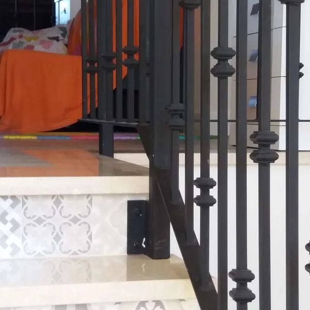 Una escalera con una barandilla negra y un sofá al fondo.