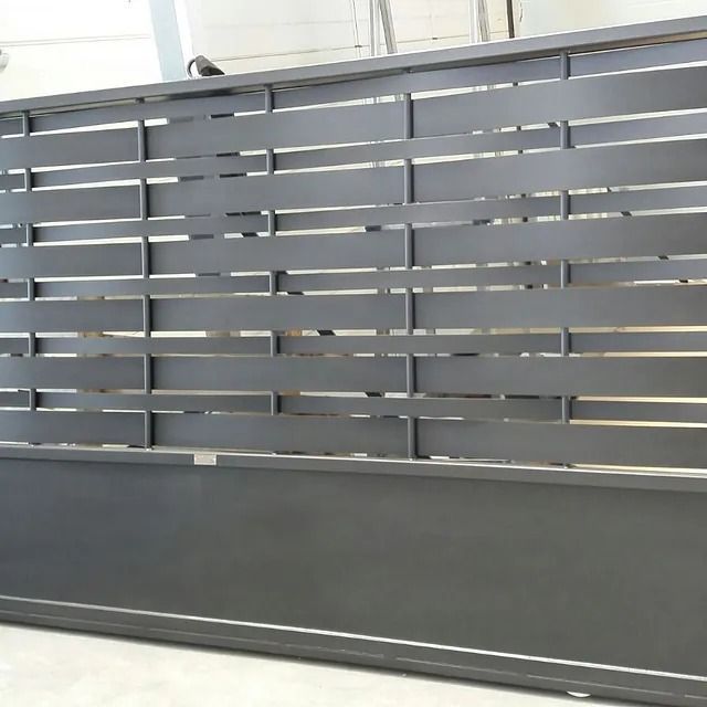 Una valla de metal negro reposa sobre un suelo de hormigón.