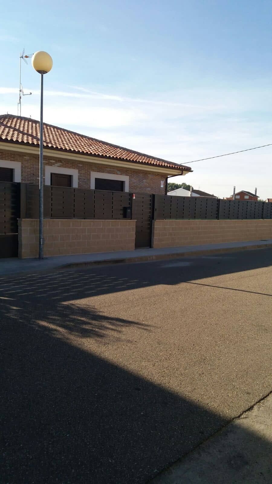 Una casa con una valla y una farola delante de ella.