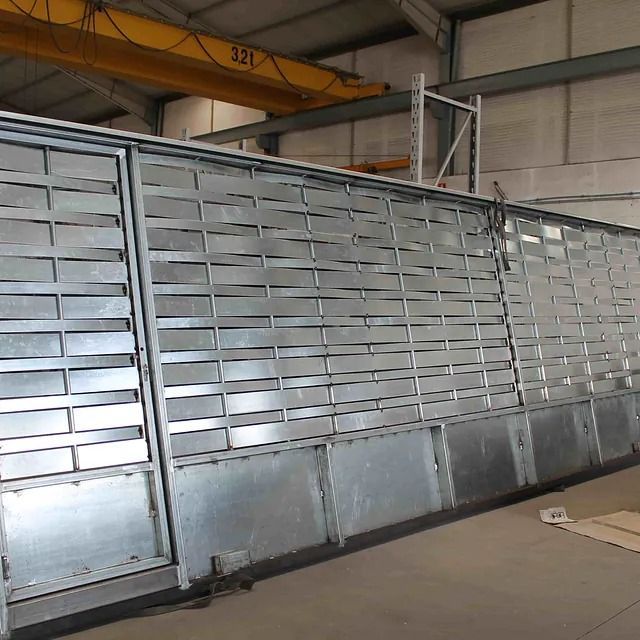 Una gran pared de metal con una grúa amarilla al fondo.