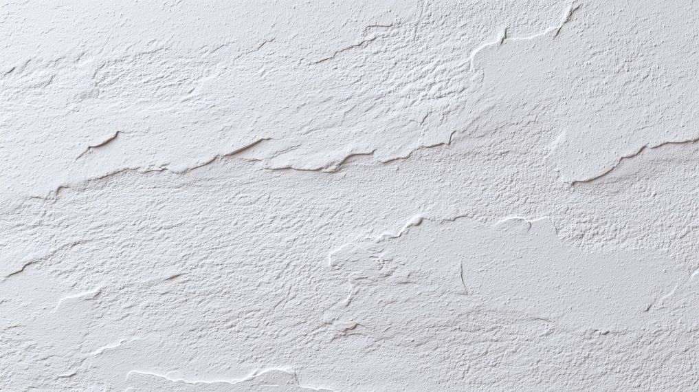 Mur en plâtre blanc texturé avec de subtiles fissures et une texture de surface irrégulière