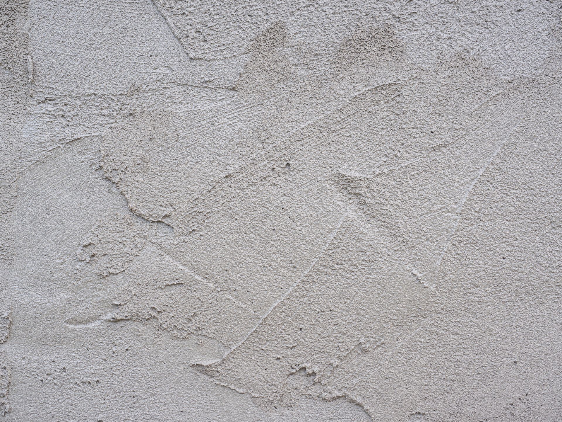 Mur gris clair texturé avec de subtiles fissures et des irrégularités.