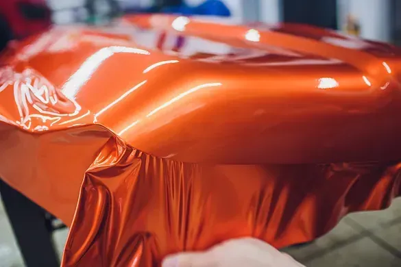 Una persona está envolviendo un automóvil en papel de aluminio naranja.