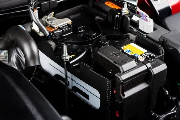 Una batería de automóvil se encuentra debajo del capó de un automóvil.