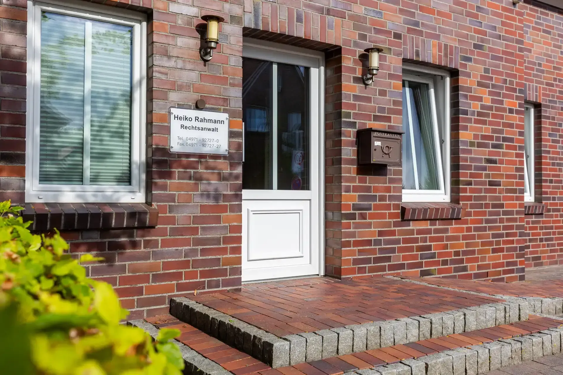 Ein Backsteingebäude mit einer weißen Tür und Stufen, die dorthin führen.