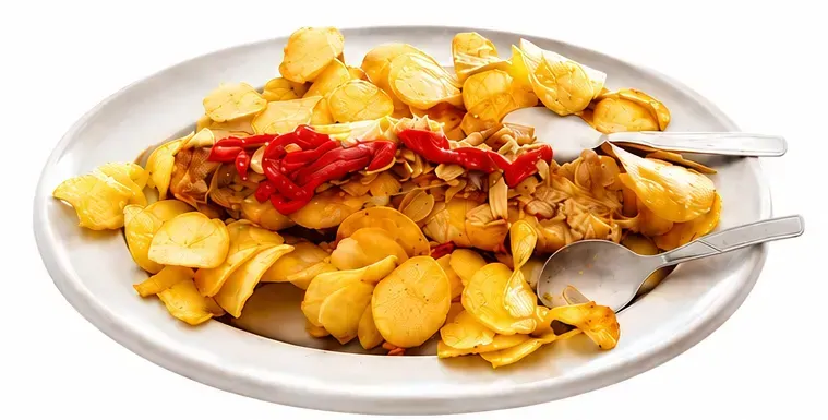 Plato de patatas fritas con ketchup, tenedor y cuchara sobre un fondo blanco.