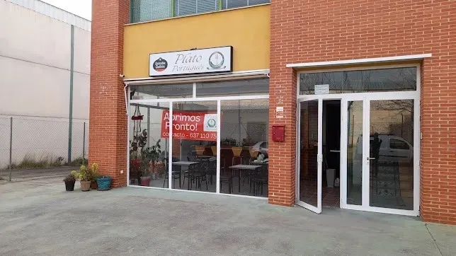 Local comercial con fachada de ladrillo, ventanas de cristal y puertas dobles de cristal, situado en una acera pavimentada.