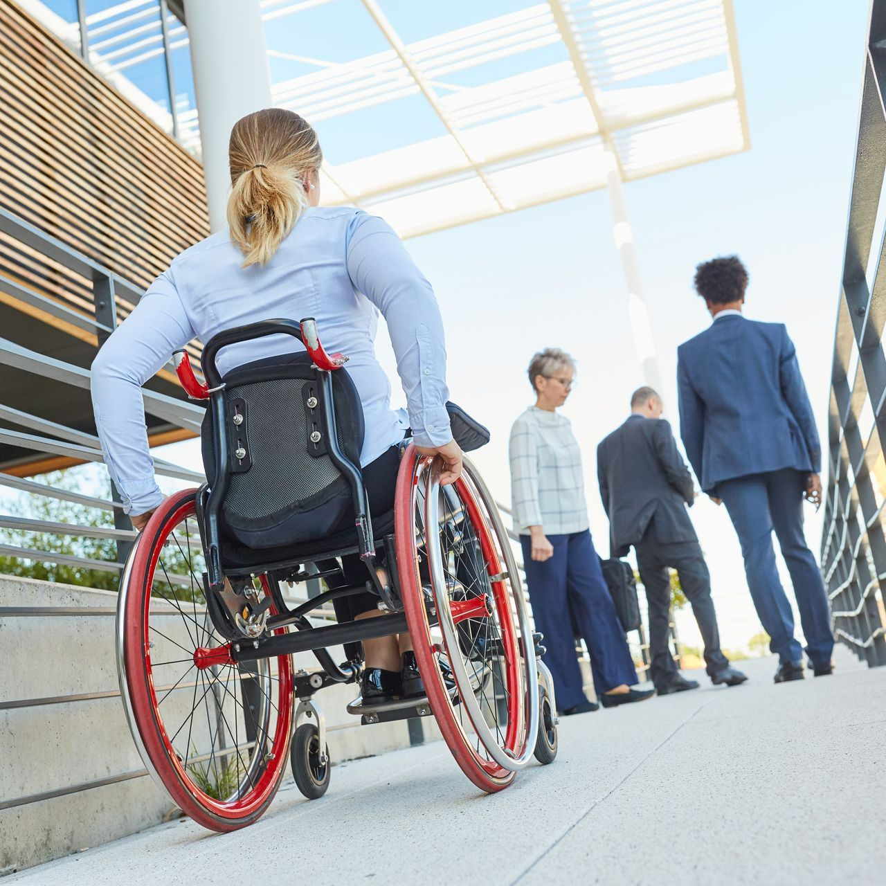 Une personne en fauteuil en roulant accédant à un bâtiment via une rampe d'accès