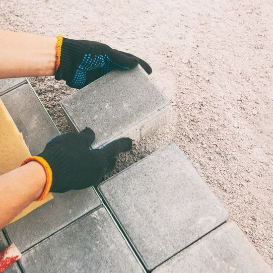 Un professionnel qui pose des pavés en béton