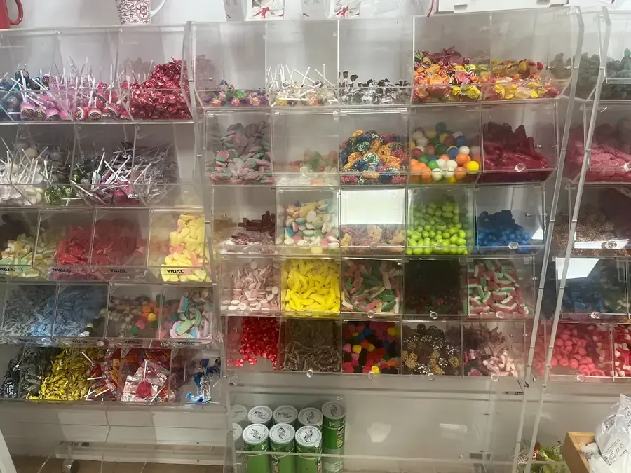 Estanterías de acrílico transparente repletas de una variedad de caramelos de colores en una tienda.
