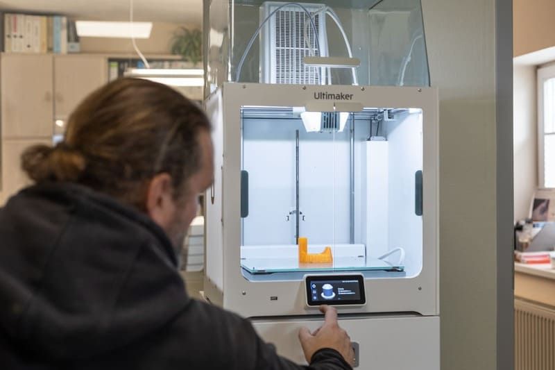 Ein Mann benutzt in einem Raum einen 3D-Drucker.