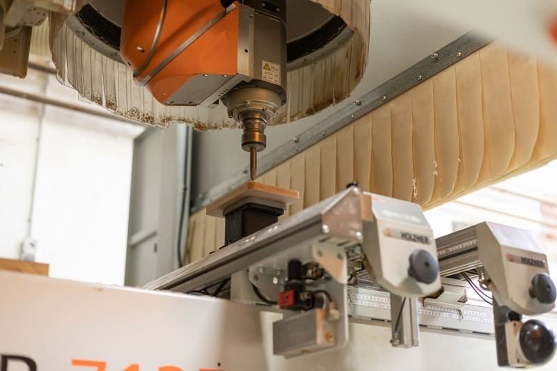 In einer Fabrik schneidet eine Maschine ein Stück Holz.