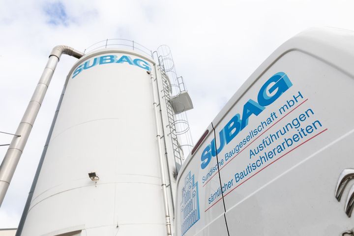 Ein weißer Lieferwagen steht vor einem Silo mit der Aufschrift „Subag“